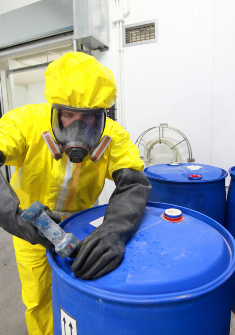 Fully protected in yellow uniform,mask,and gloves professional filling barrel with chemicals